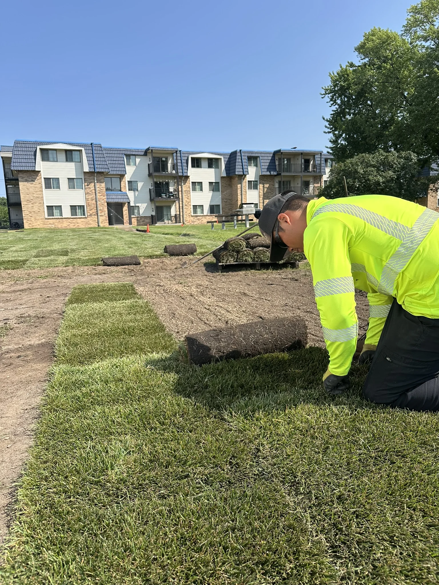 Clearline Outdoor crew member placing a roll of sod at a multifamily property