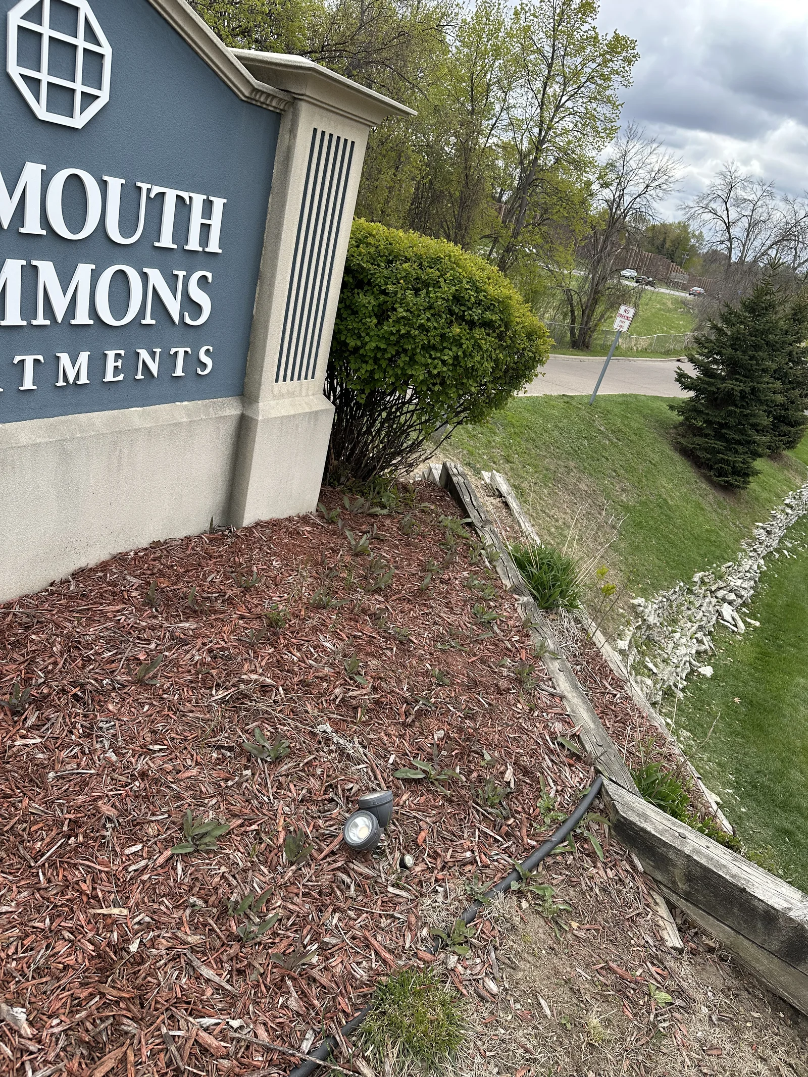 Thin, aging mulch bed with a cracked timber edge at a multifamily property before renovation