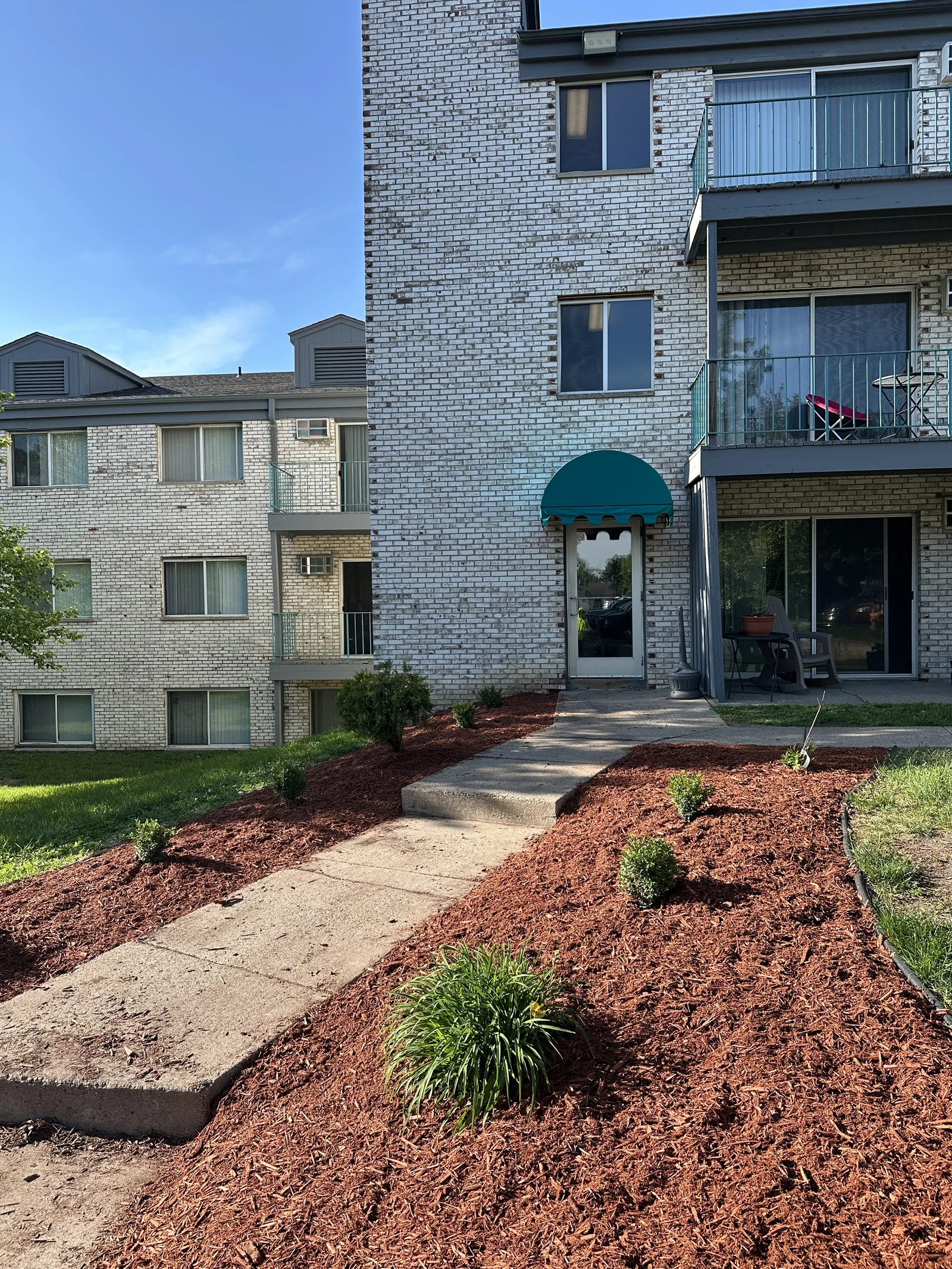Freshly mulched and planted bed near a building entrance at Plymouth Commons