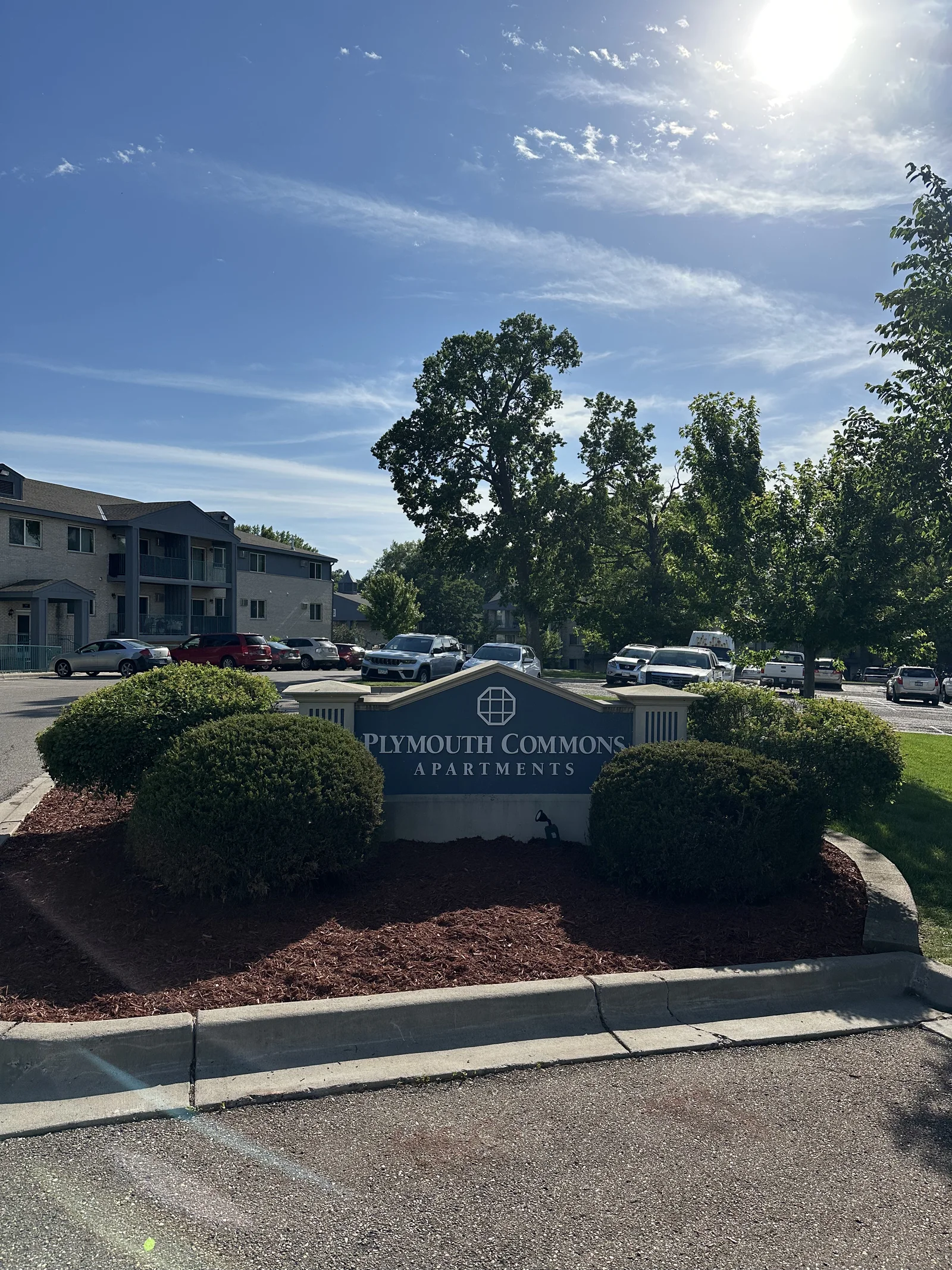 Plymouth Commons monument sign with fresh mulch and full plantings in summer sun