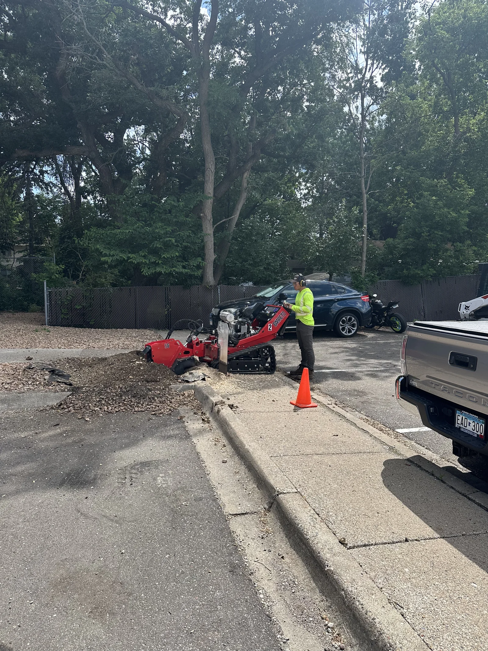 Stump grinder machine parked at the curb after removing old tree stumps at Cove Apartments