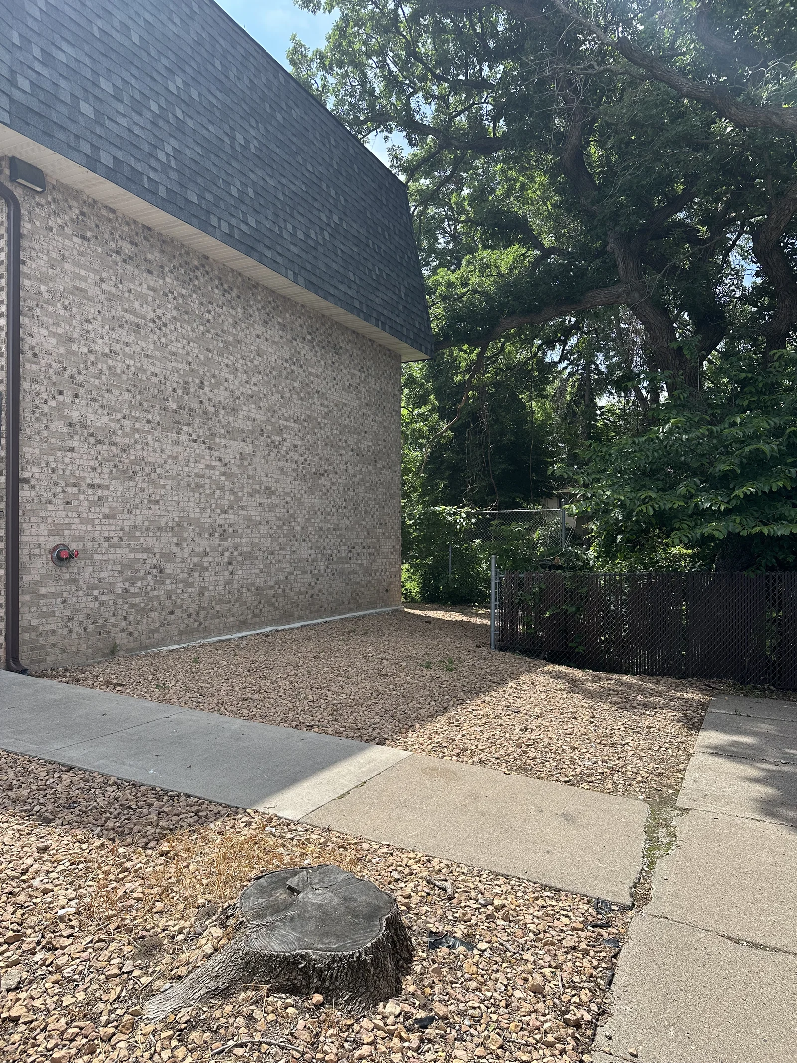 Building corner at Cove Apartments before renovation, with an old stump left in the rock bed