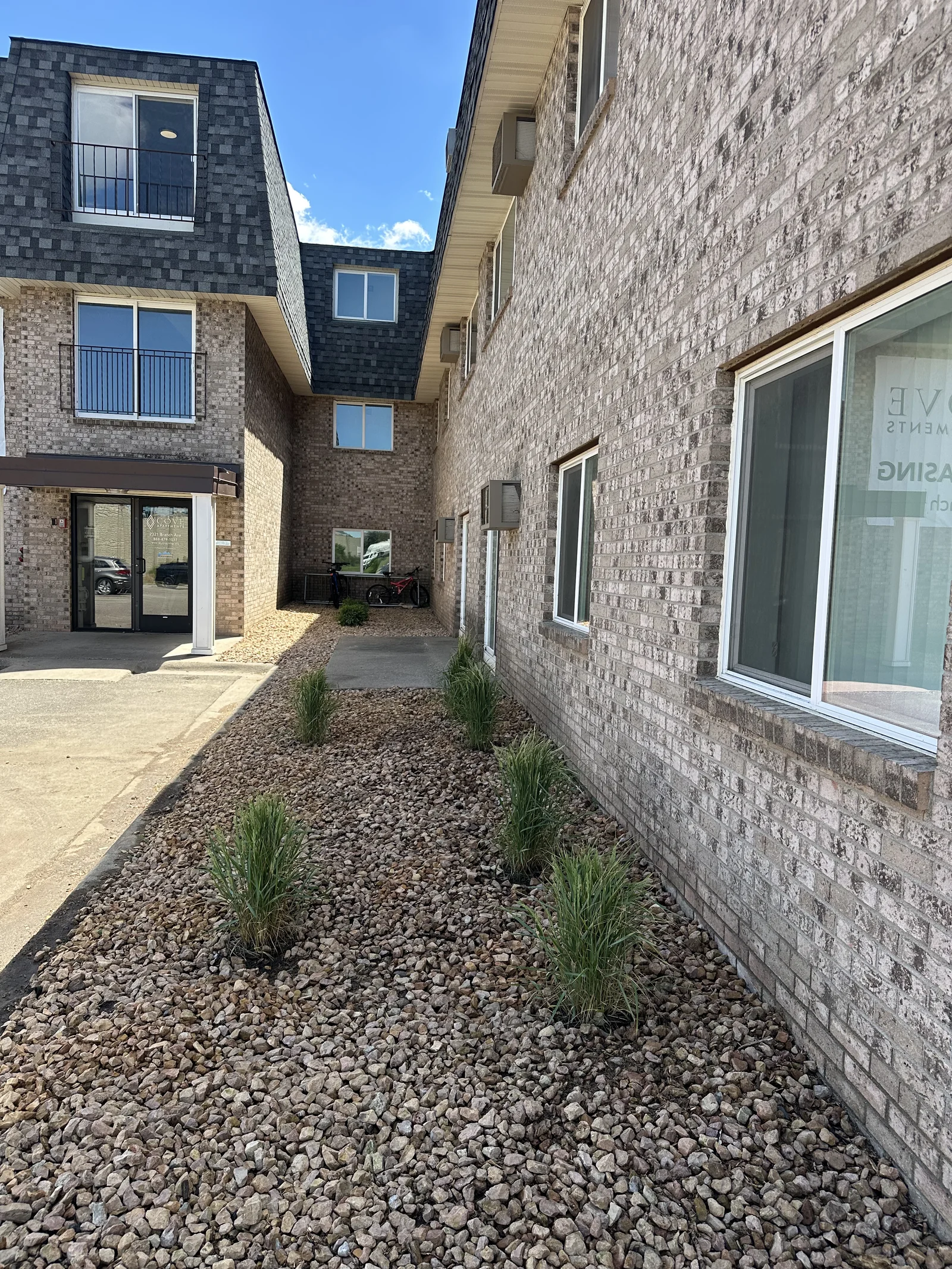 Same walkway near the leasing office at Cove Apartments after renovation, with new shrubs and ornamental grasses