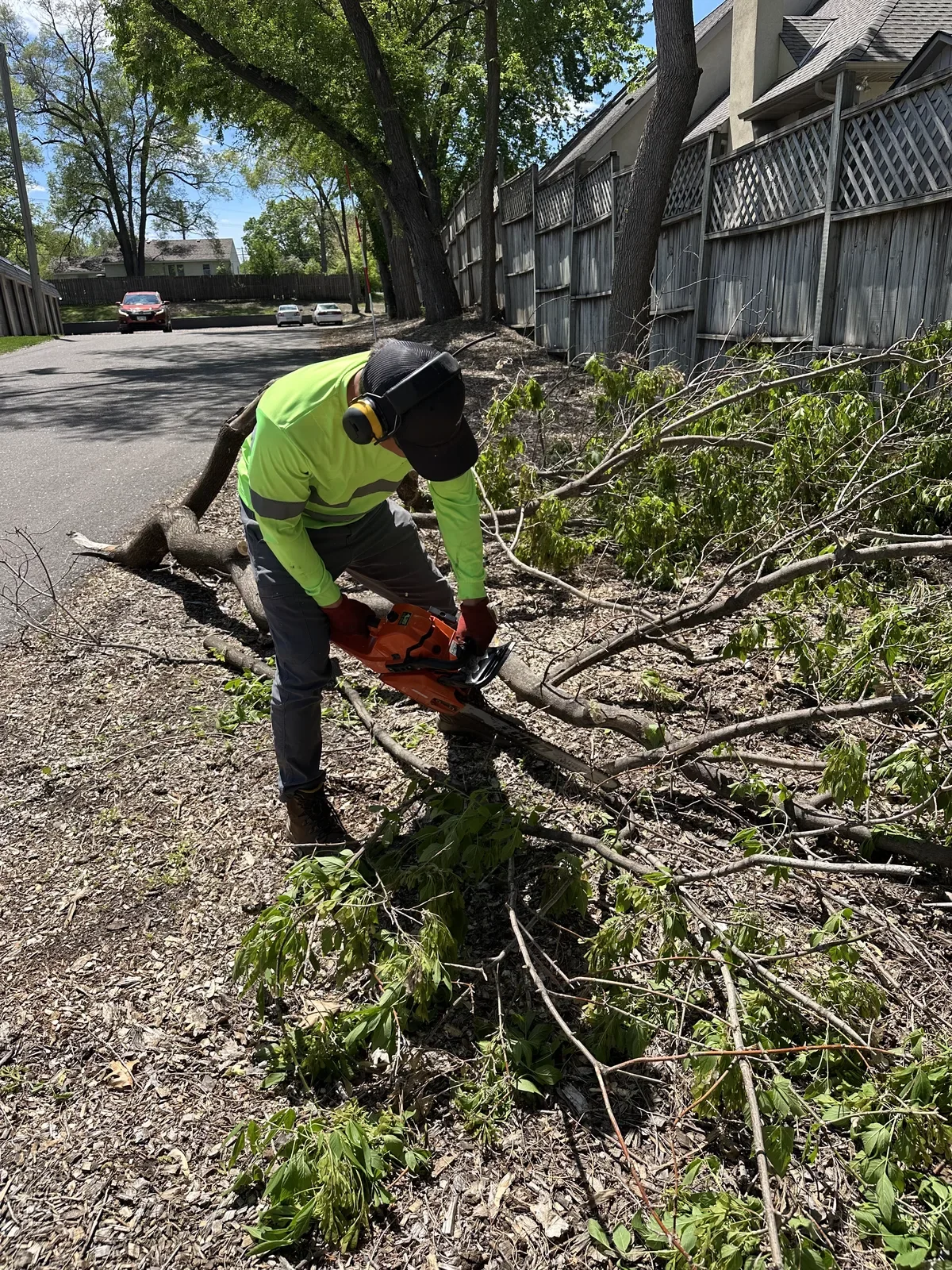 Clearline Outdoor crew cutting up a fallen tree branch at Ninety9 Lofts in Champlin, Minnesota