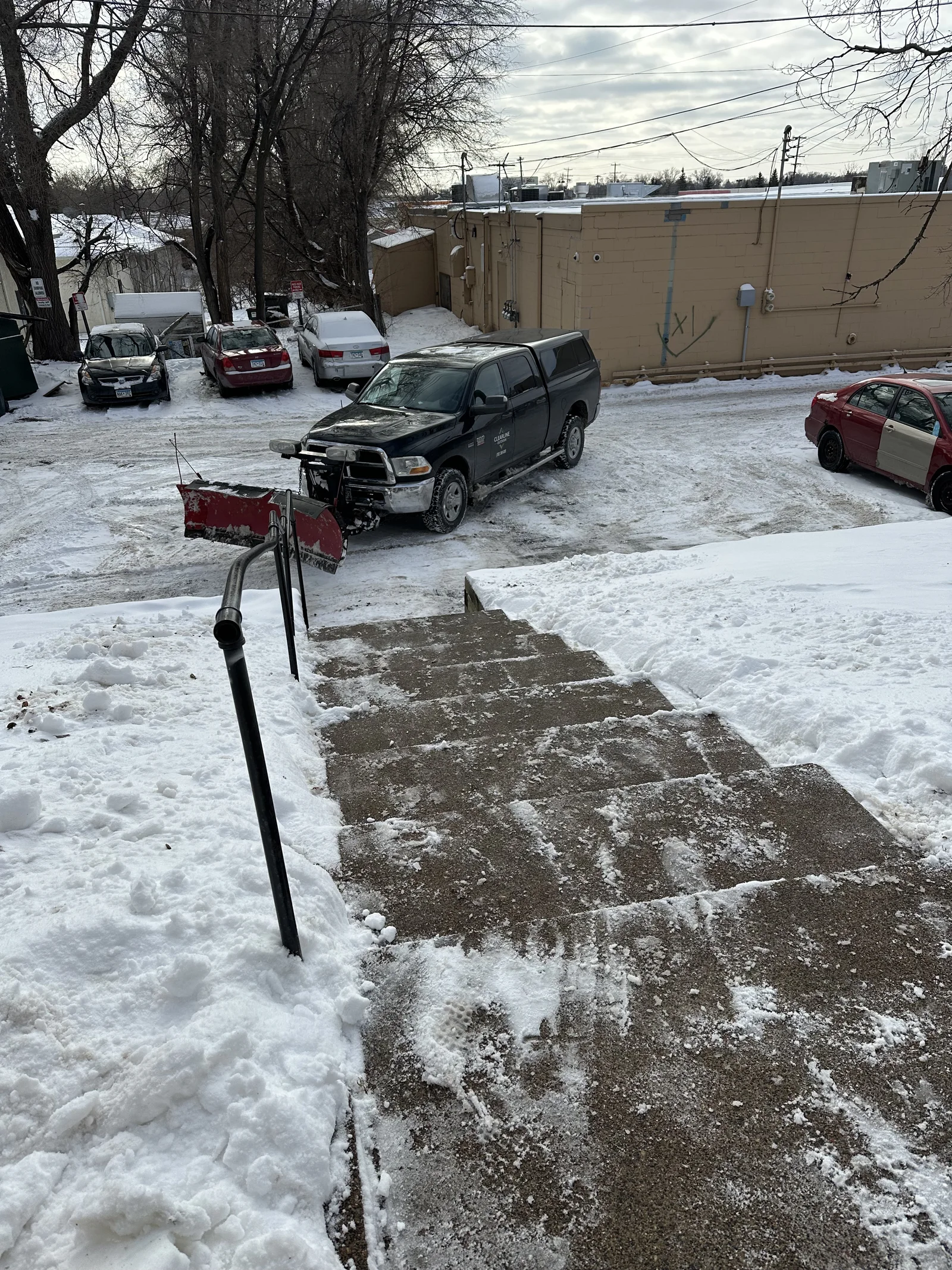 Clearline Outdoor plow truck next to cleared and salted stairs at Tyler St Apartments in Columbia Heights, Minnesota