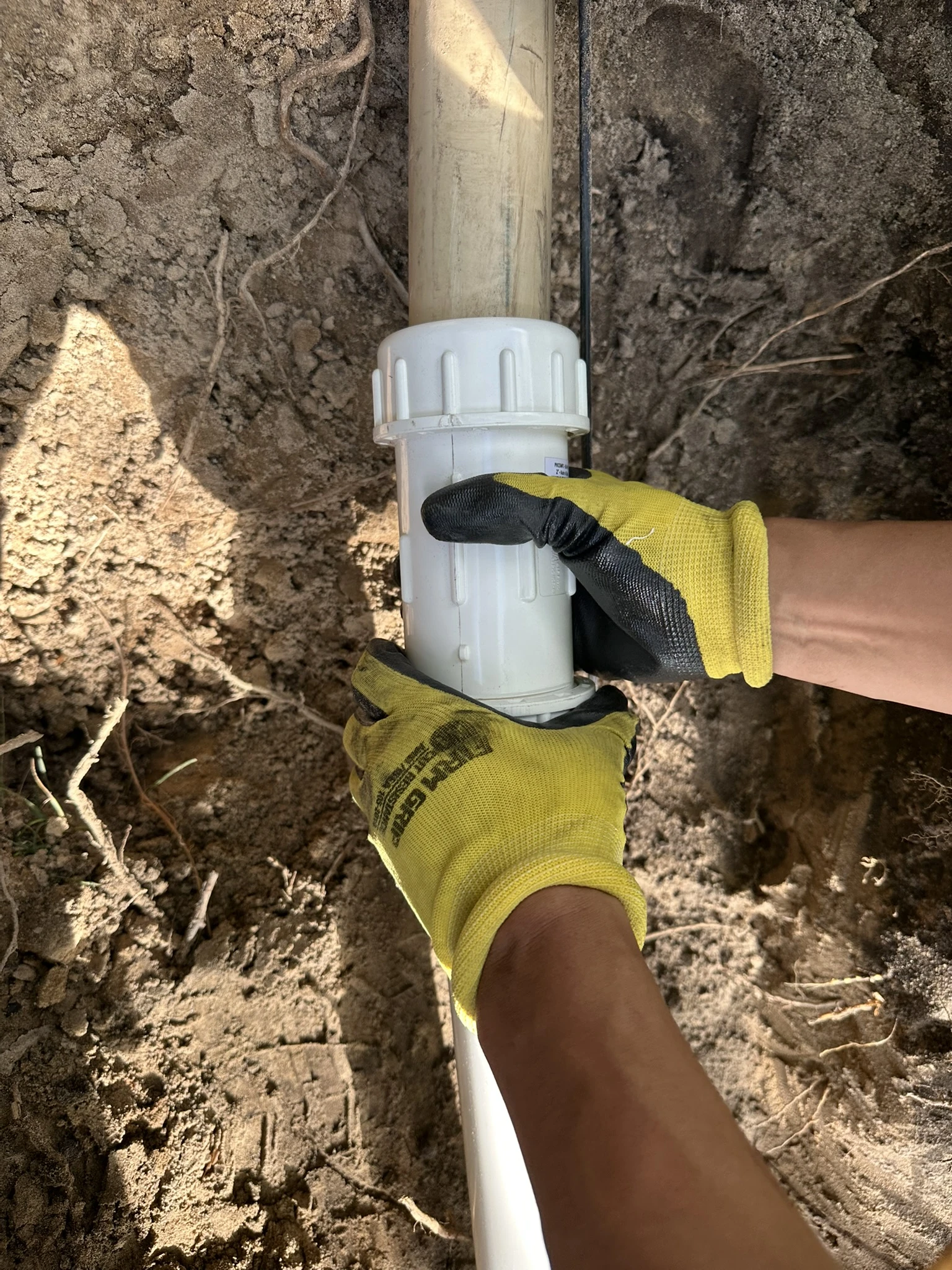 Clearline Outdoor technician assembling an irrigation pipe fitting during system installation at a North Metro property