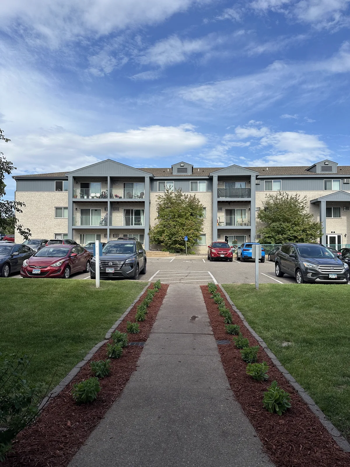 Freshly planted flower beds along the entrance walkway at Plymouth Commons Apartments in Plymouth, Minnesota