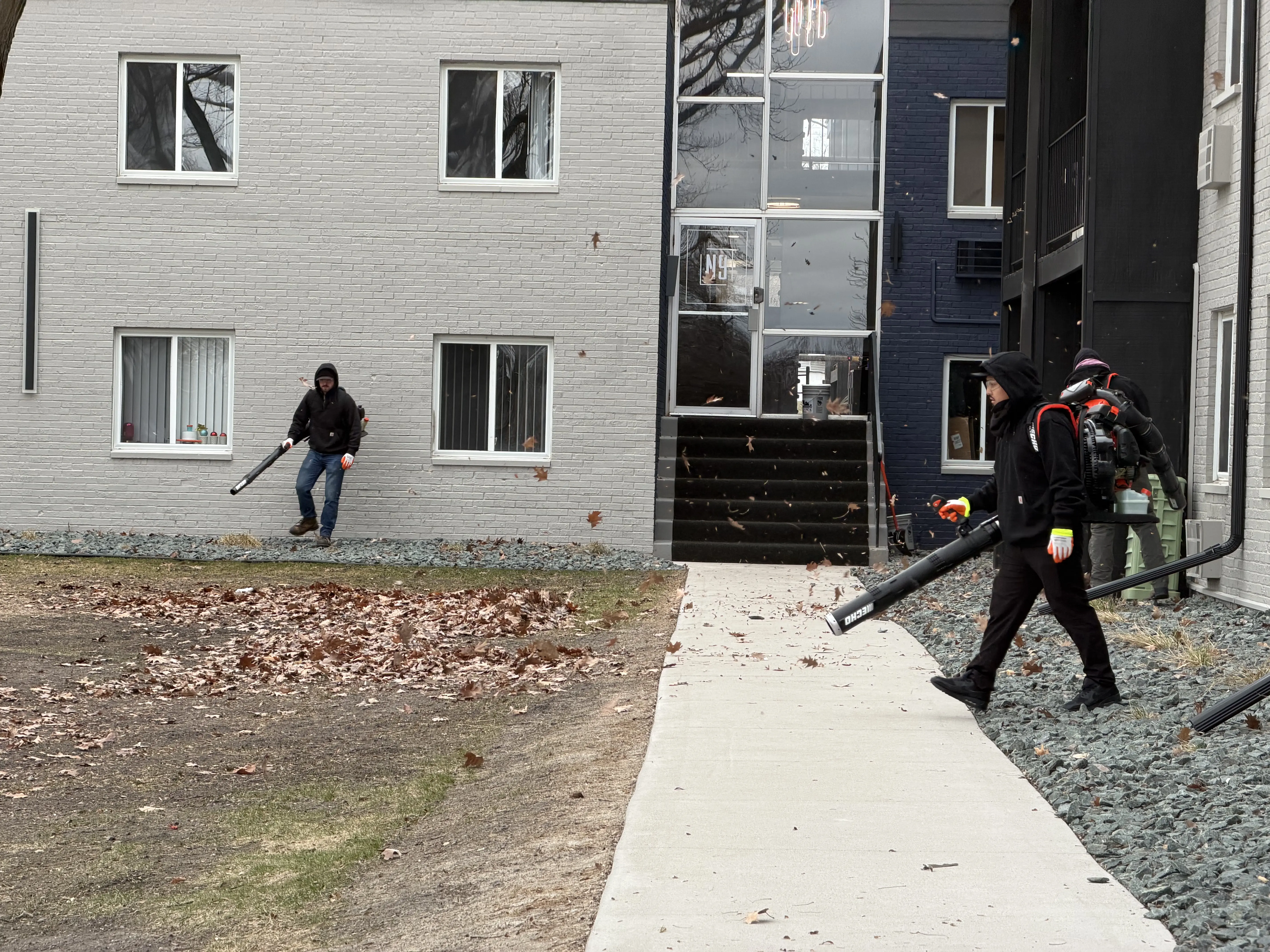 Clearline Outdoor crew blowing fall leaves at the entrance walkway of Ninety9 Lofts in Champlin, Minnesota